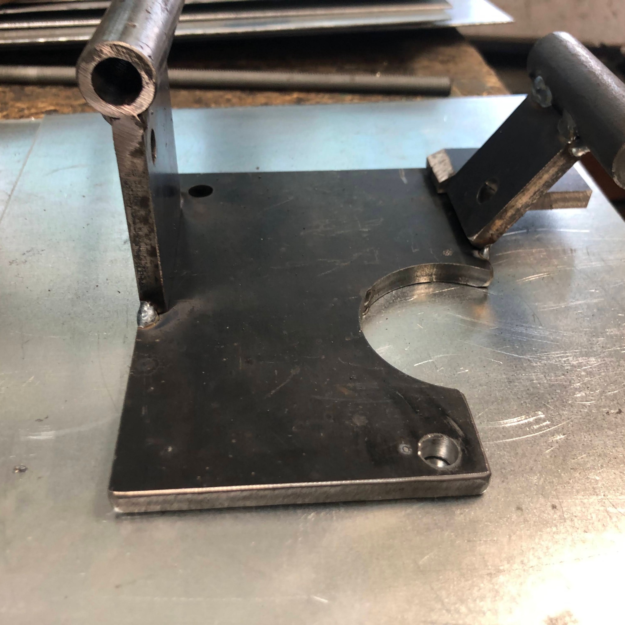 Metalowy element konstrukcyjny z rurami, spawany, z widocznymi śladami obróbki, leżący na metalowym stole warsztatowym.