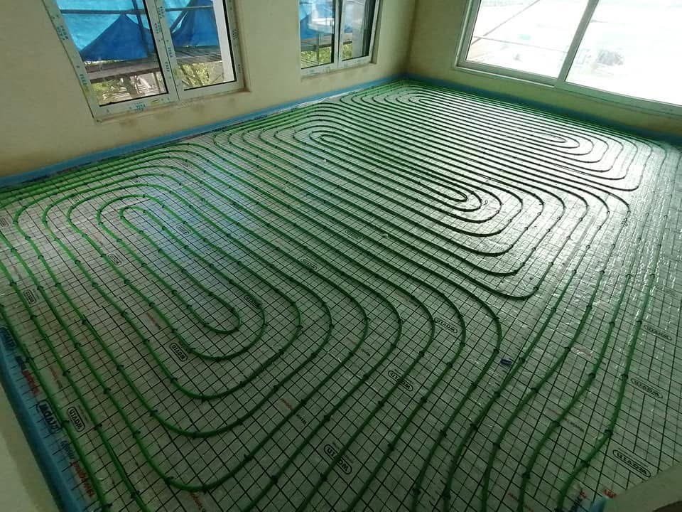 Zielone rury ogrzewania podłogowego ułożone na podkładzie w Zabrzu, widoczne okna i naturalne światło.