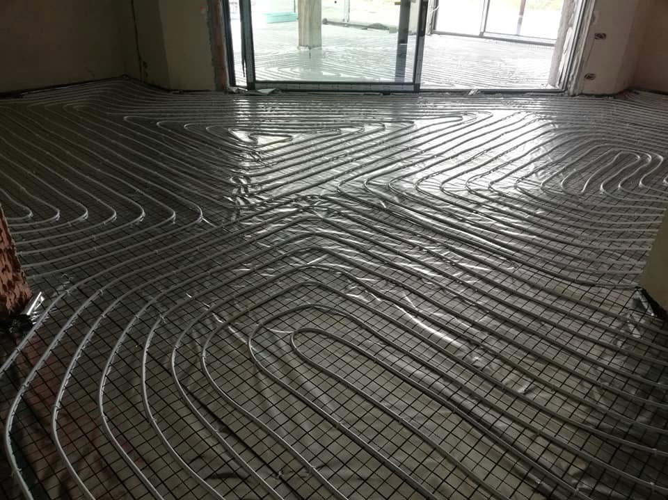 Montaż ogrzewania podłogowego w Zabrzu: rury grzewcze ułożone na siatce, przygotowane do zalania wylewką, widok na okno tarasowe.