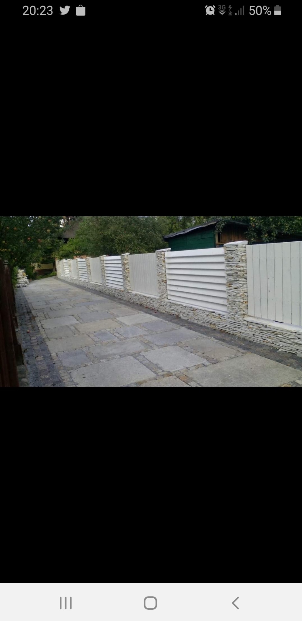 Nowoczesne ogrodzenie panelowe z elementami kamiennymi w Domaradzu, widoczne z perspektywy chodnika z kostki brukowej.