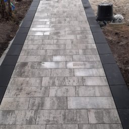 Zakład Usług BRUK-JAN TROCHOWSKI JAN - Ułożony chodnik z kostki brukowej w odcieniach szarości, obrzeża z ciemnej kostki. W tle dom z numerem 4 i fragment ogrodu z widocznymi pracami ziemnymi.