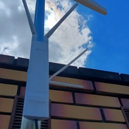 Bogdan Popłoński Clever-Tech - Antena telekomunikacyjna Signaflex na tle błękitnego nieba, zamontowana na budynku w Białej Rawskiej. Widok z dołu, skierowany ku górze.