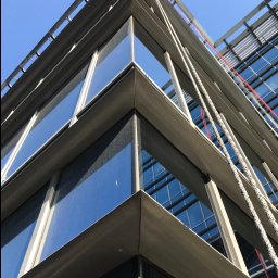 LA Project - Nisko kątowe ujęcie narożnika przeszklonego biurowca z linami do mycia okien na wysokości, część okien jest brudna.