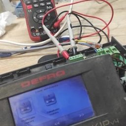 ElexFix Dawid Hłubek - Multimetr wskazuje napięcie na panelu sterowania DEPRO KIP v4. Diagnostyka elektroniki przemysłowej w toku, widoczne przewody i złącza. Pomiar napięcia 232.88V.