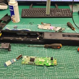 ElexFix Dawid Hłubek - Rozłożony soundbar na macie serwisowej, widoczne narzędzia (śrubokręty, lutownica), elementy elektroniczne. Sprzęt w trakcie naprawy, na biurku monitor i klawiatura.