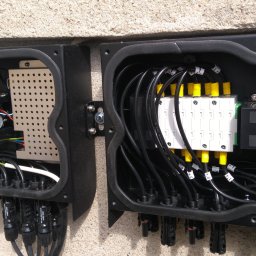 51 Mieczysław Terlecki - Rozdzielnica elektryczna z okablowaniem w skrzynce, widok z bliska. Instalacja fotowoltaiczna w Poznaniu. Elementy z żółtymi i białymi oznaczeniami, czarne kable.