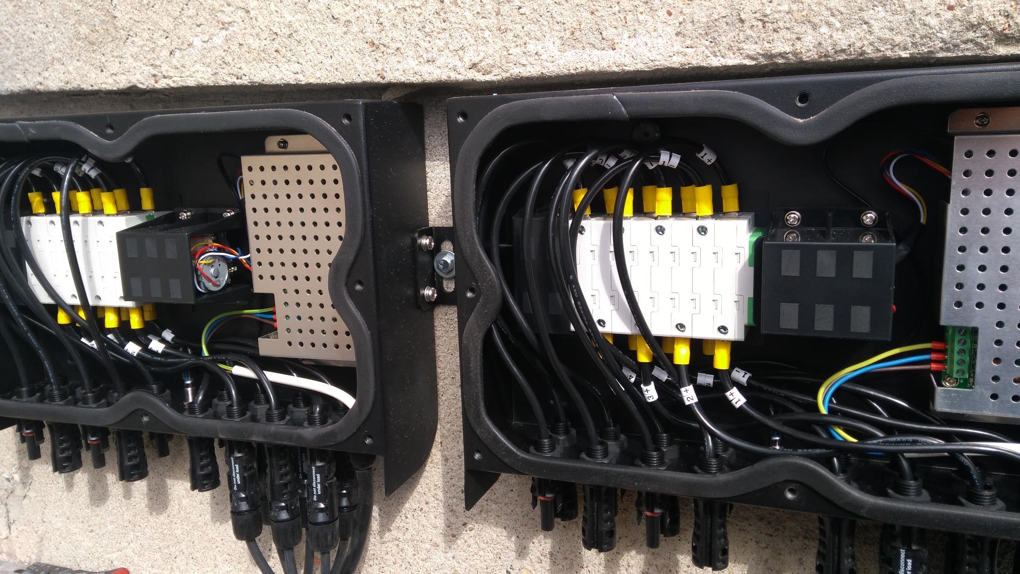 Rozdzielnica elektryczna z okablowaniem w skrzynce, widok z bliska. Instalacja fotowoltaiczna w Poznaniu. Elementy z żółtymi i białymi oznaczeniami, czarne kable.