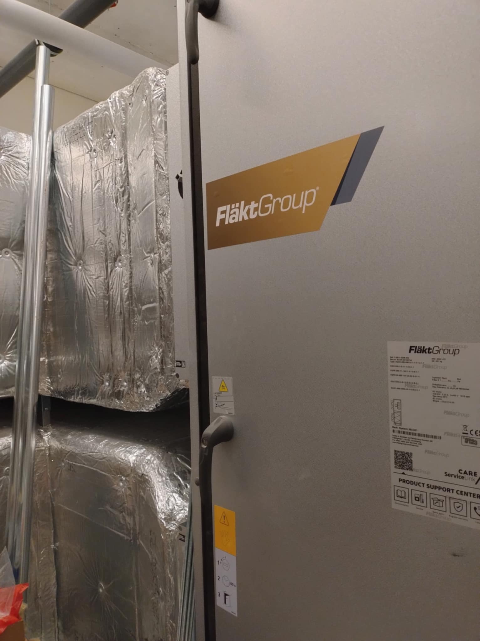 Centrala wentylacyjna FläktGroup z izolacją termiczną, widoczna etykieta informacyjna i logo producenta na obudowie.