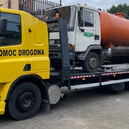 Firma Handlowo Usługowa Jarosław JANIK - Żółta laweta DAF z napisem 'POMOC DROGOWA' przewozi białą ciężarówkę z pomarańczowym zbiornikiem na płyny.