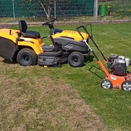 JAROSŁAW KOŚMICKI - Żółty traktorek do koszenia trawy i wertykulator na trawniku, z widoczną różnicą w wyglądzie trawy po zabiegu wertykulacji.
