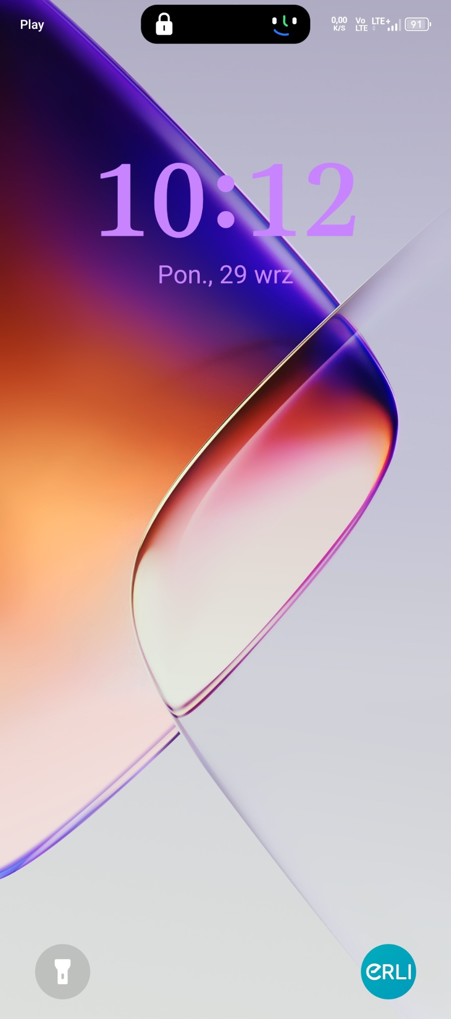 Ekran smartfona z wyświetlonym zegarem 10:12, datą 29 września i abstrakcyjnym tłem w odcieniach fioletu, pomarańczy i bieli. Widoczne ikony stanu baterii i połączenia.