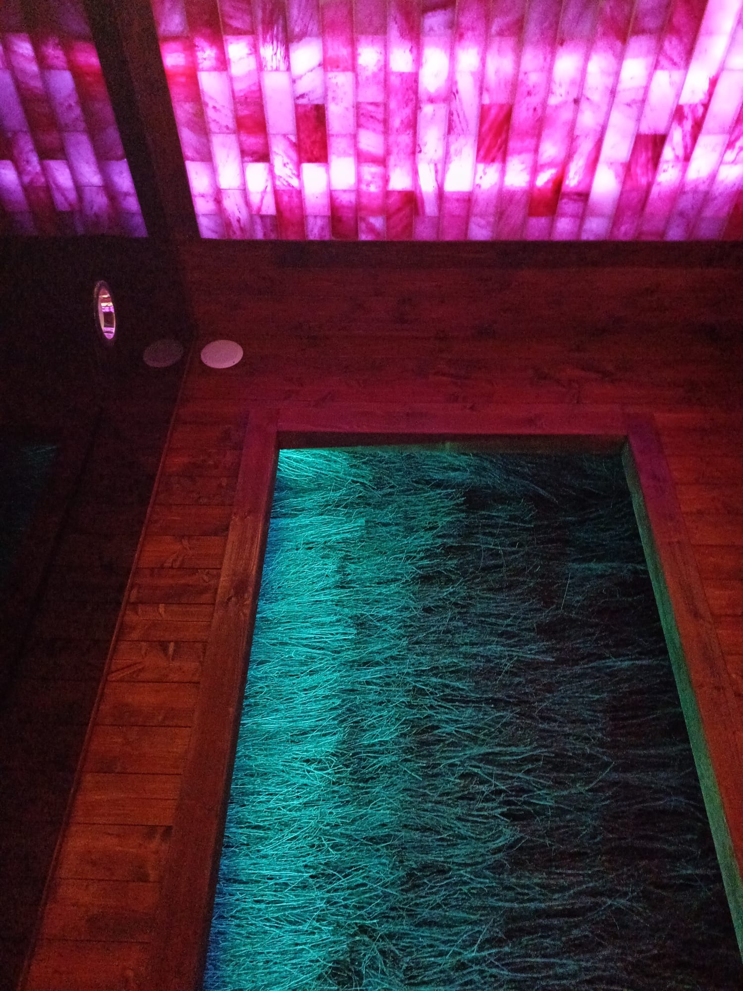 Fragment wnętrza sauny solnej z podświetlanym sufitem z cegieł solnych i ścianami z drewna. W tle widoczna podświetlana na zielono podłoga.
