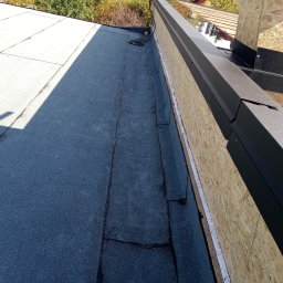 Vasil Irhovtsii - Fragment dachu pokrytego papą, z widocznymi obróbkami blacharskimi w kolorze czarnym i deskowaniem z płyty OSB. Widoczny kabel na dachu.