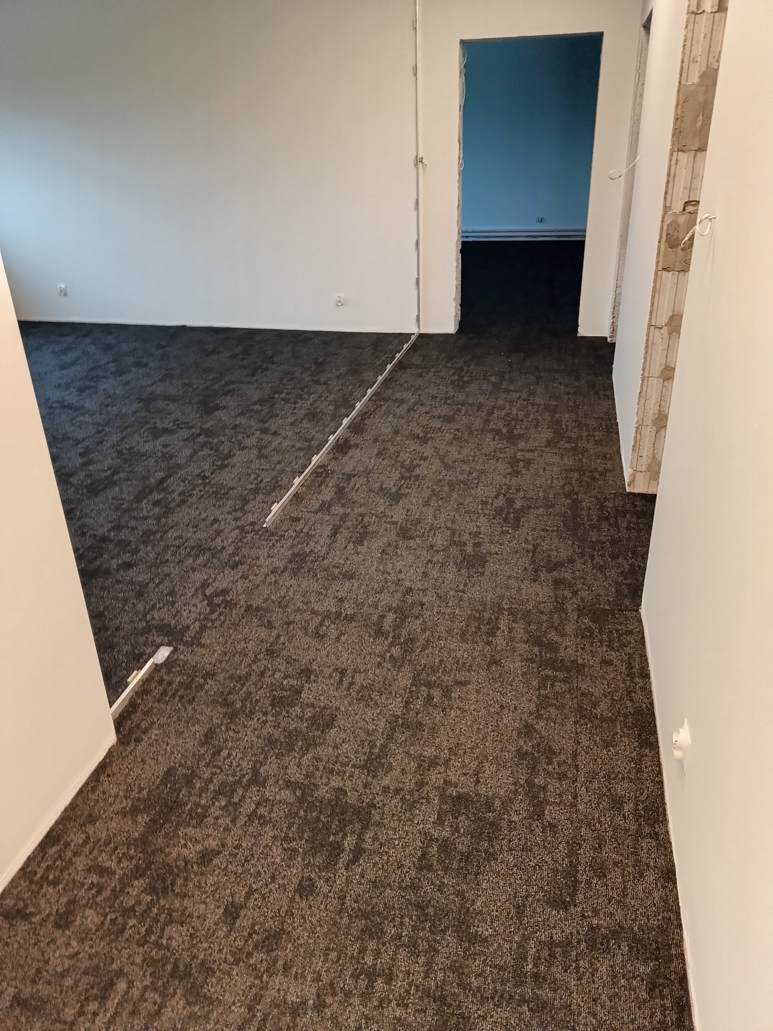 Ciemna, wzorzysta podłoga w trakcie montażu w Gdyni, widoczne listwy przypodłogowe i przygotowane przejście do kolejnego pomieszczenia.