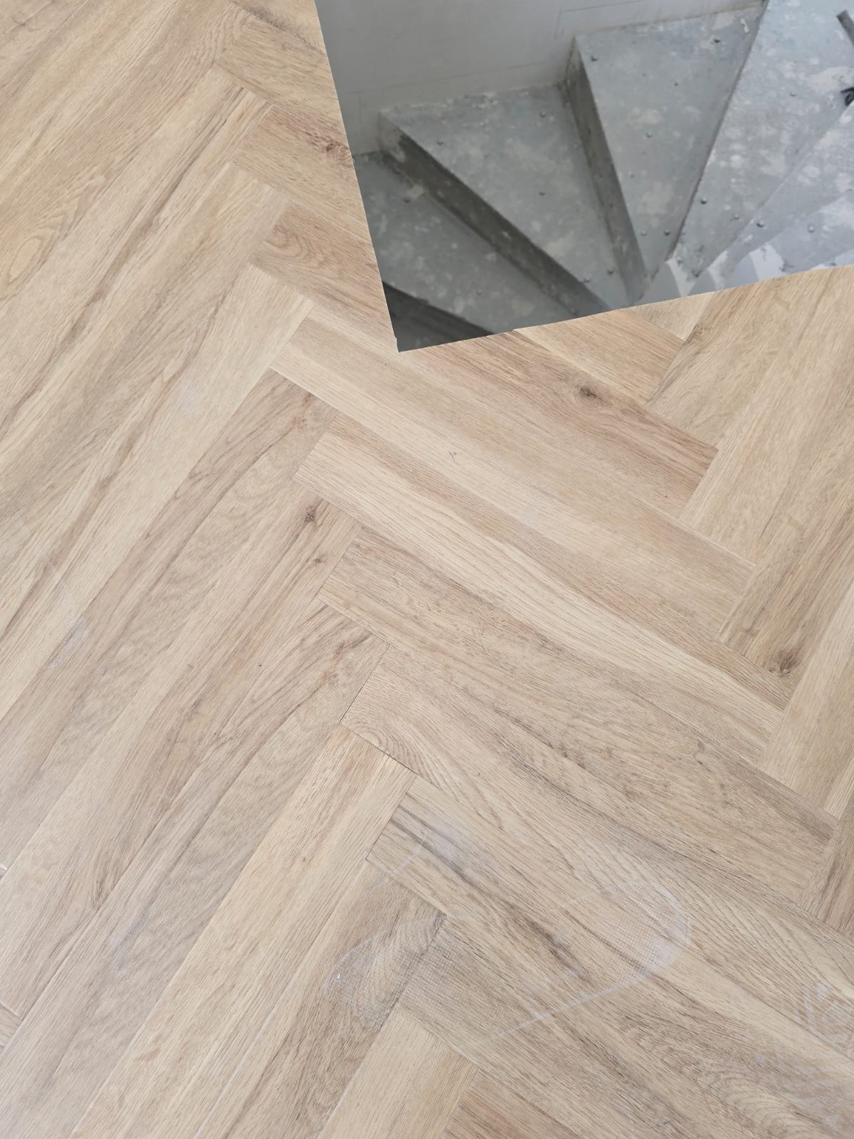 Jasne panele ułożone w jodełkę francuską w Gdyni, z widocznym fragmentem betonowych schodów w tle.