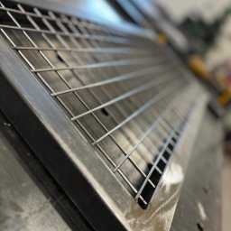 Michał Jerzewski - Surowa, metalowa konstrukcja kratowa z grubą ramą, leżąca na warsztatowym stole, widoczna z perspektywy, z rozmytym tłem warsztatu.