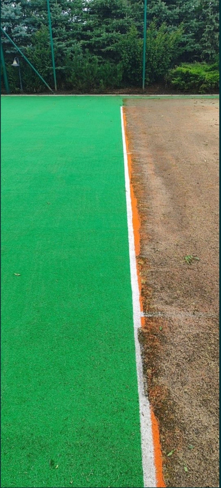 Porównanie stanu nawierzchni sportowej przed i po czyszczeniu: intensywnie zielona, czysta powierzchnia po lewej stronie kontrastuje z brudną, ziemistą powierzchnią po prawej, oddzielone białą...