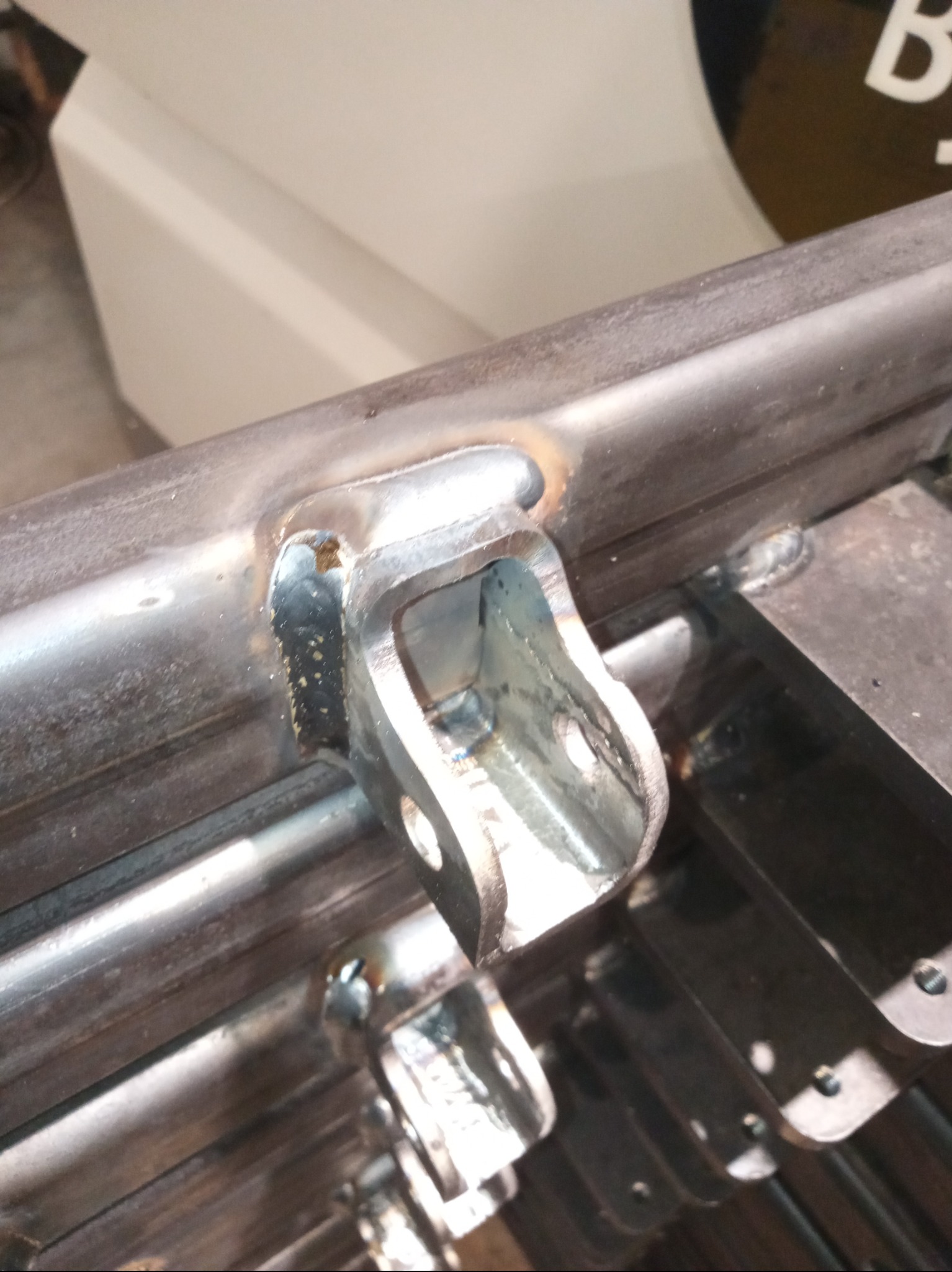 Spoina łącząca metalowy element z rurą, widoczne ślady po spawaniu, surowy wygląd, metaliczna powierzchnia, detale łączenia.