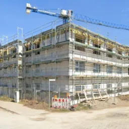 Budynek domu starców w Hildesheim w trakcie montażu stolarki okiennej na rusztowaniach, widoczny żuraw budowlany.