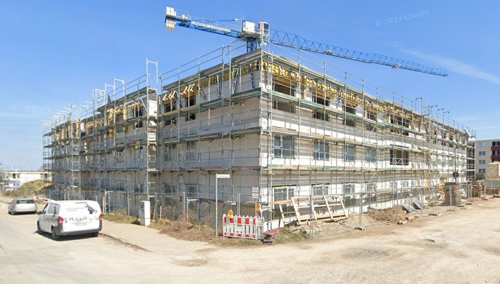 Budynek domu starców w Hildesheim w trakcie montażu stolarki okiennej na rusztowaniach, widoczny żuraw budowlany.