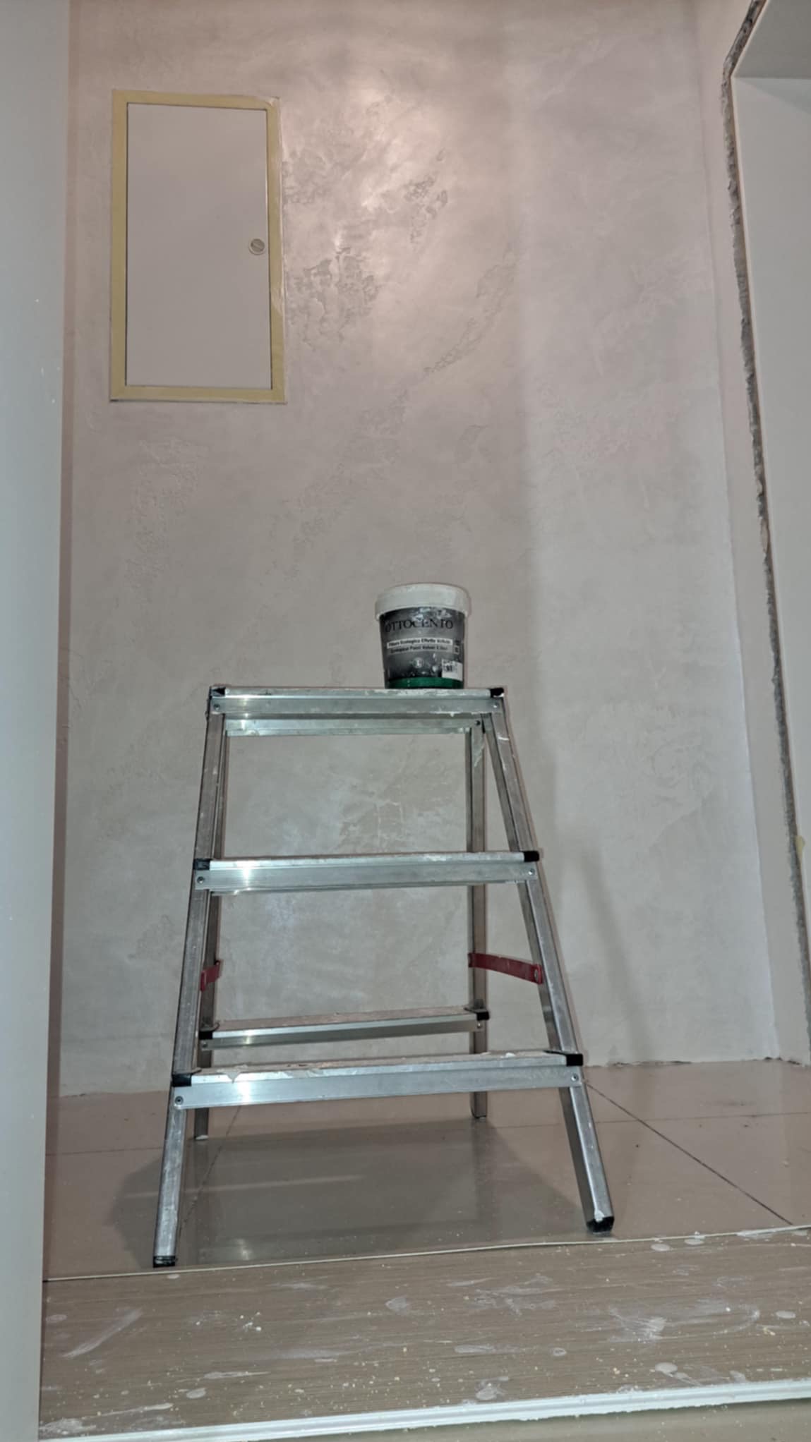 Ściana pokryta dekoracyjną farbą Ottocento z efektem aksamitu, widoczna drabina aluminiowa z puszką farby na górze oraz klapa rewizyjna w ścianie.