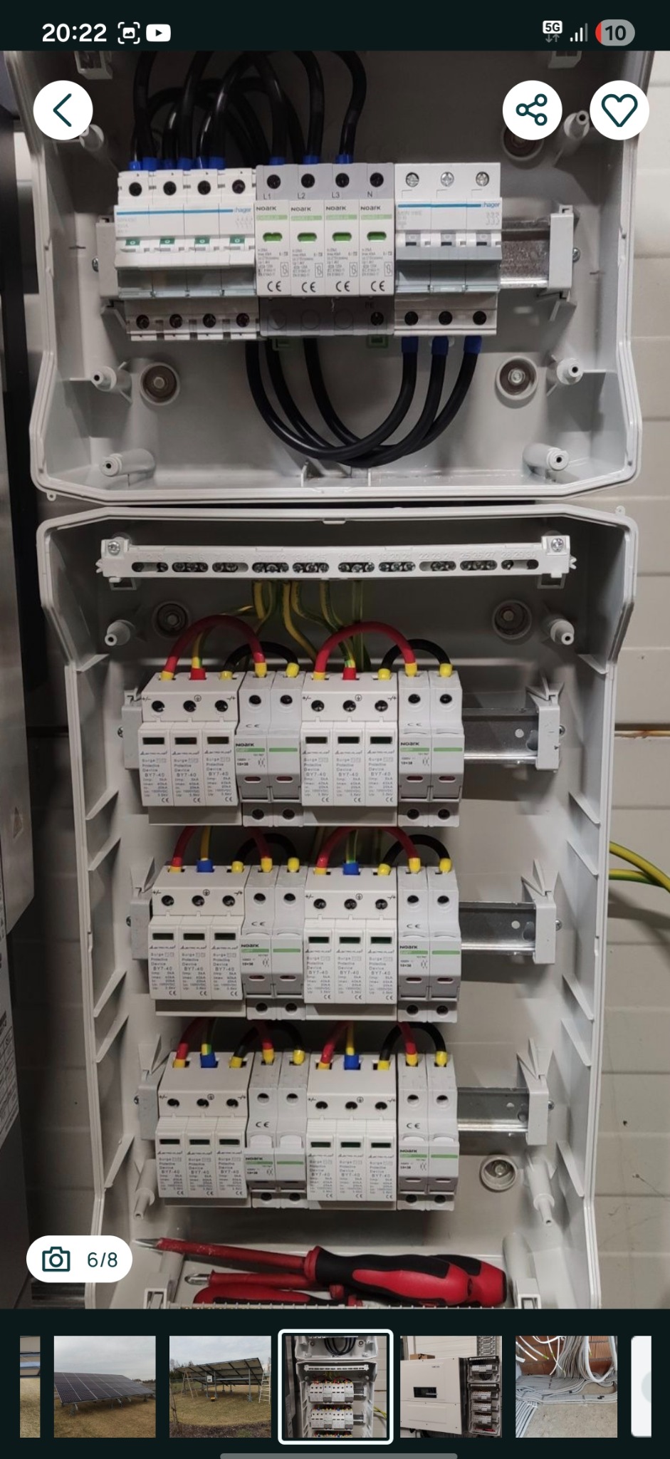 Otwarta skrzynka elektryczna z bezpiecznikami i przewodami, widoczne narzędzia. Instalacja elektryczna wewnątrz obudowy, zabezpieczenia nadprądowe i różnicowoprądowe.