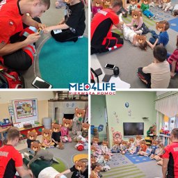 Med4Life Jakub Olbrich - Pierwsza Pomoc - Instruktor w czerwonej koszulce ratownika medycznego demonstruje dzieciom w przedszkolu, jak używać pulsoksymetru na palcu dziewczynki, a także bandażuje nogę dziecka, podczas zajęć z pierwszej...