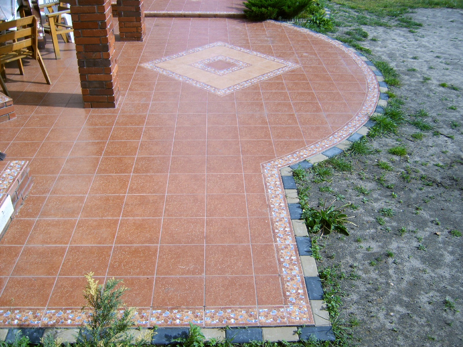Wyłożony terakotą taras z dekoracyjnym wzorem rombu i obrzeżem z mozaiki, widok z góry.