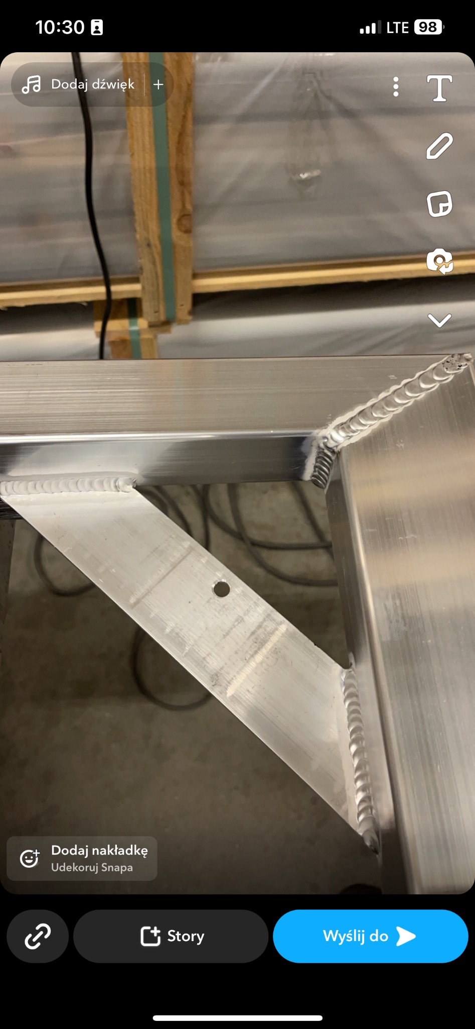 Detal spawu łączącego aluminiowe profile, widoczne ślady spawania, otwór w jednym z elementów, konstrukcja w trakcie tworzenia.