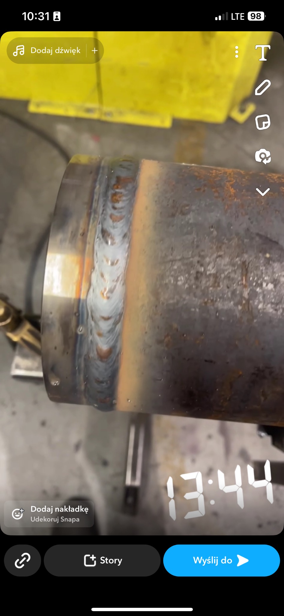 Spoina na rurze stalowej, widoczne ślady ciepła i odbarwienia metalu, surowe warunki warsztatowe.