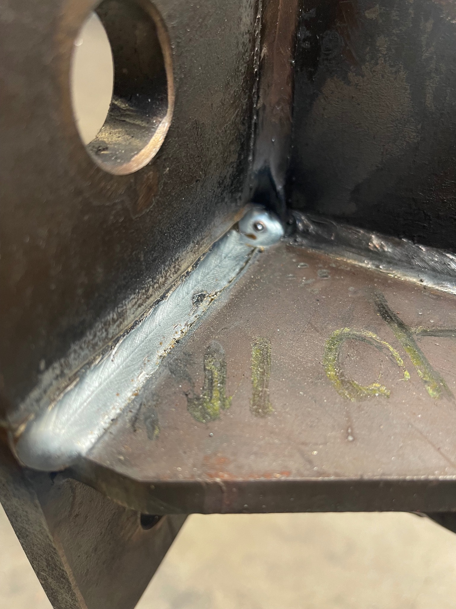 Spoina narożnikowa na konstrukcji stalowej z widocznymi śladami po spawaniu i zielonymi oznaczeniami.