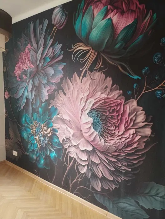 Ściana z fototapetą w duże, kolorowe kwiaty w odcieniach różu, zieleni i błękitu. Na podłodze parkiet w jodełkę. Widoczny fragment ściany i podłogi w pomieszczeniu.