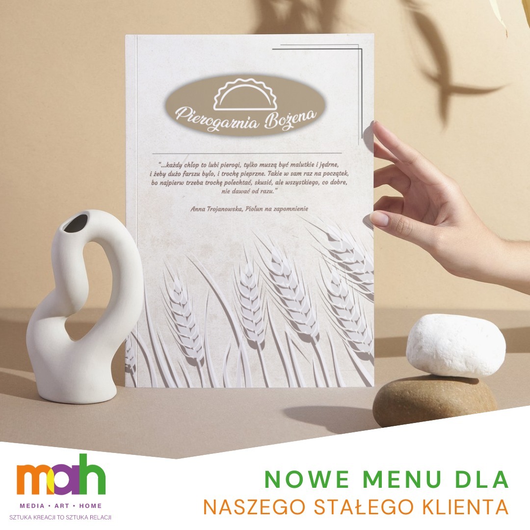 Projekt nowego menu dla Pierogarni Bożena, z cytatem Anny Trojanowskiej i motywem pszenicy, prezentowany obok białej, abstrakcyjnej wazy i kamieni, trzymany przez dłoń.