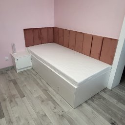 MARTINOS MEBLE NA WYMIAR Marcin Hełmiński - Białe łóżko z szufladami i tapicerowanym, brązowym wezgłowiem na tle różowej ściany. Obok biała szafka nocna. Parkiet w odcieniach szarości.