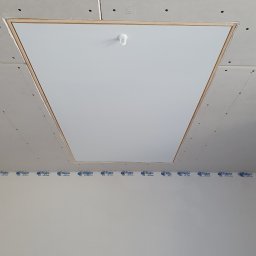 WYKOŃCZENIA WNĘTRZ-GRZEGORZ BATOR - Biała klapa rewizyjna w suficie z płyt gipsowo-kartonowych, widoczne łączenia płyt i taśma Rigips, sufit przed szpachlowaniem i malowaniem.