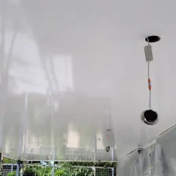 Błyszczący, świeżo pomalowany sufit w trakcie instalacji oświetlenia punktowego, ściany częściowo zabezpieczone folią ochronną.