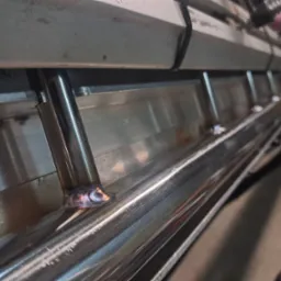 Detal spawu ramy metalowej konstrukcji z okrągłych profili, widoczne ślady spawania i obróbki metalu.