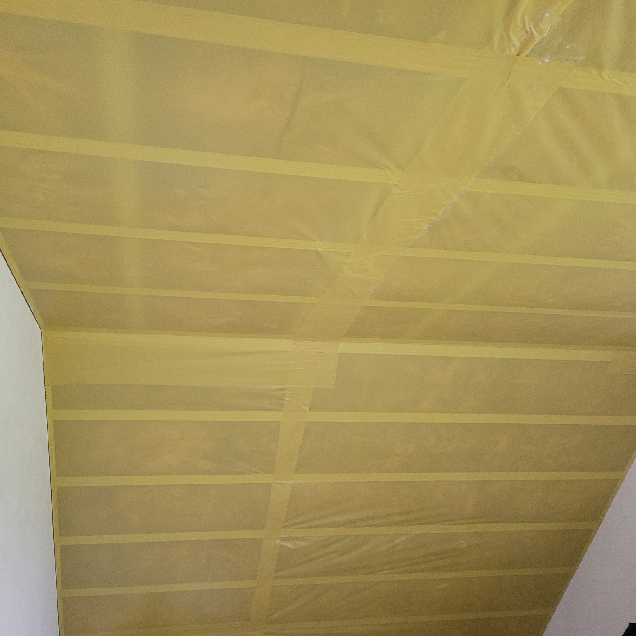 Sufit zabezpieczony folią malarską i taśmą przed malowaniem, widok z dołu.