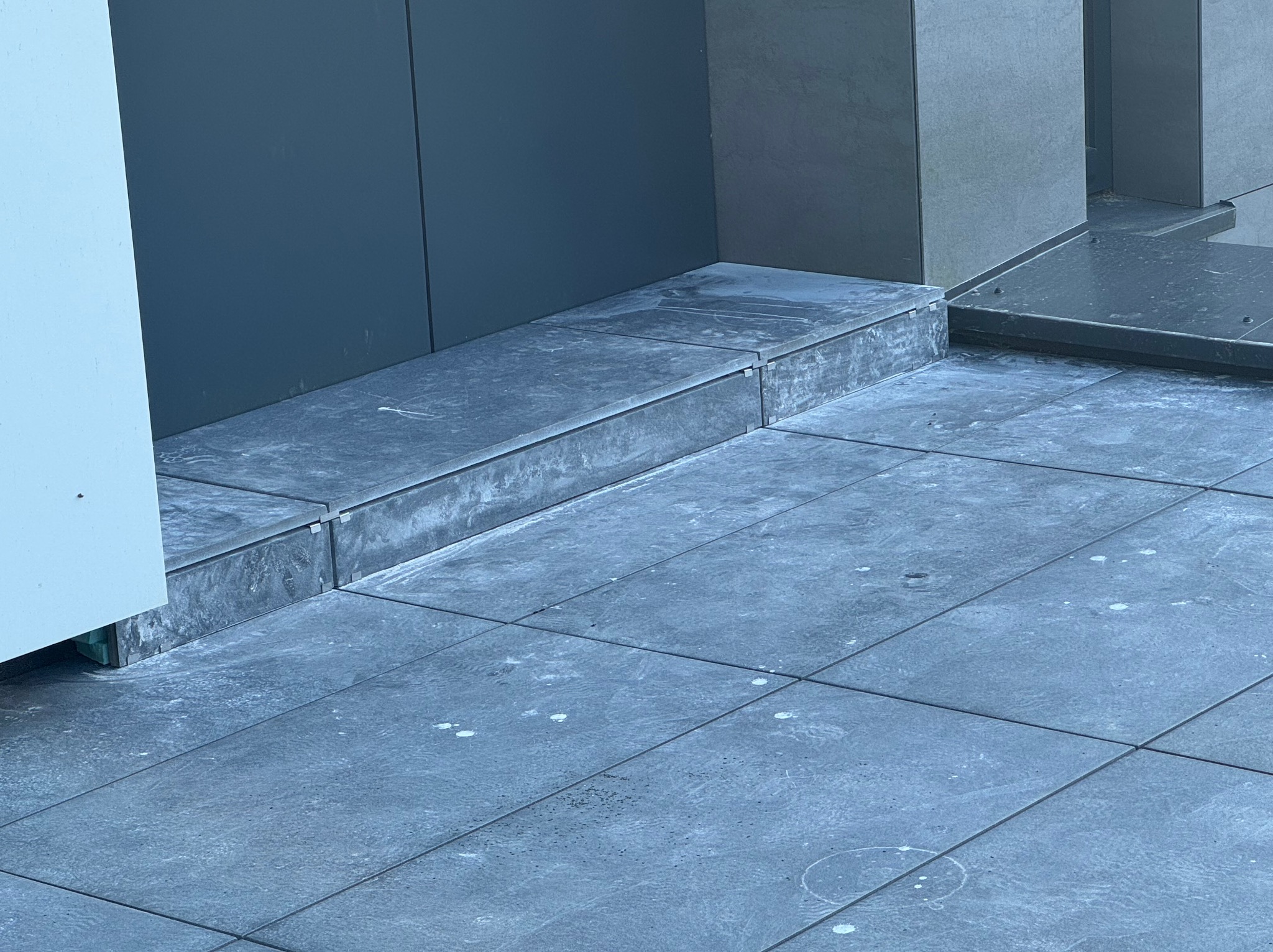 Wykończony taras betonowy z szarych płyt, widoczne detale łączeń i impregnacji. Minimalistyczny design, nowoczesne wykończenie.