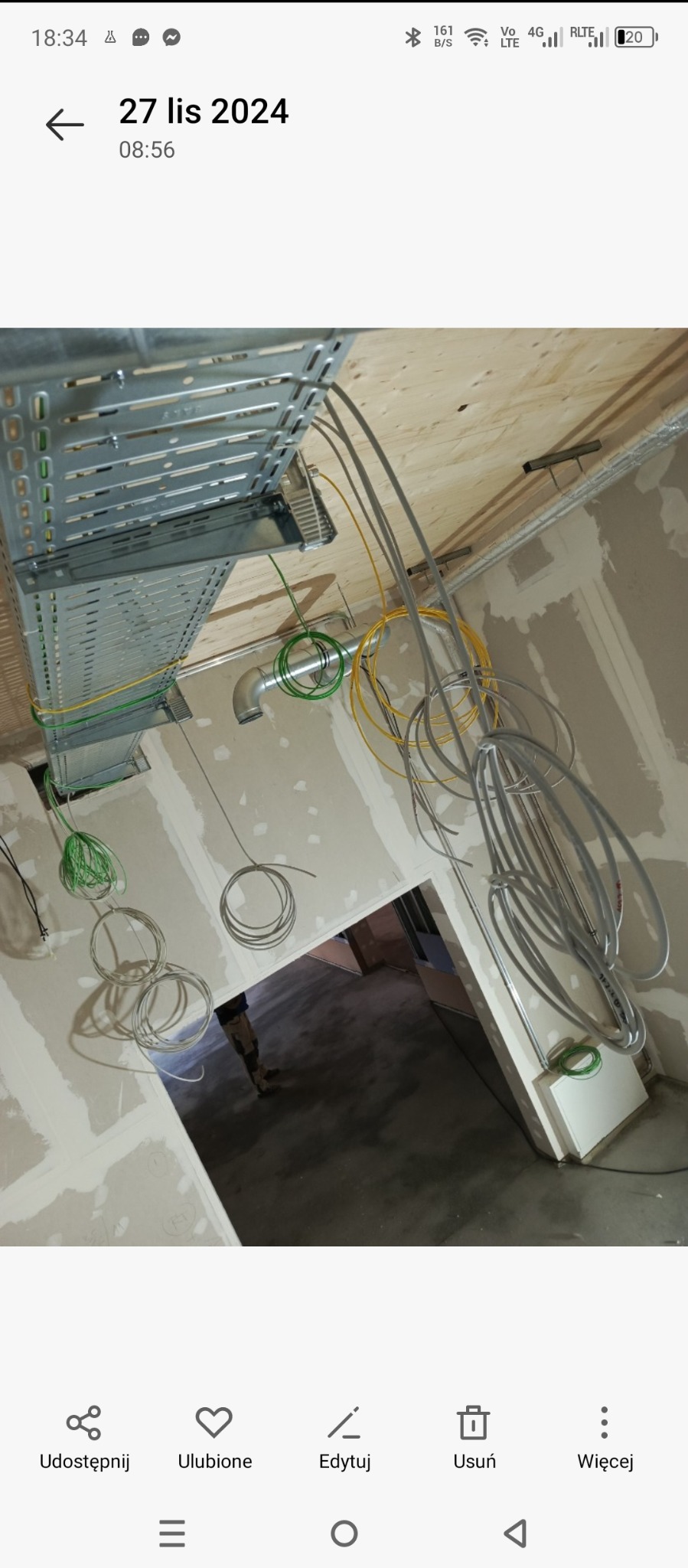 Instalacja elektryczna i wentylacyjna w surowym wnętrzu biurowym, widoczne koryta kablowe pod sufitem, przewody elektryczne w różnych kolorach oraz kanały wentylacyjne, ściany po szpachlowaniu...