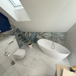 ART-INVEST Damian Solarski - Nowoczesna łazienka na poddaszu ze skośnym sufitem, białą wolnostojącą wanną, toaletą, marmurową podłogą i ścianą z motywem kwiatowym, oświetlona oknem dachowym.