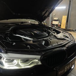 B44 Serwis - Czarny samochód BMW z otwartą maską w warsztacie, widoczny silnik i reflektory, tablica rejestracyjna B44