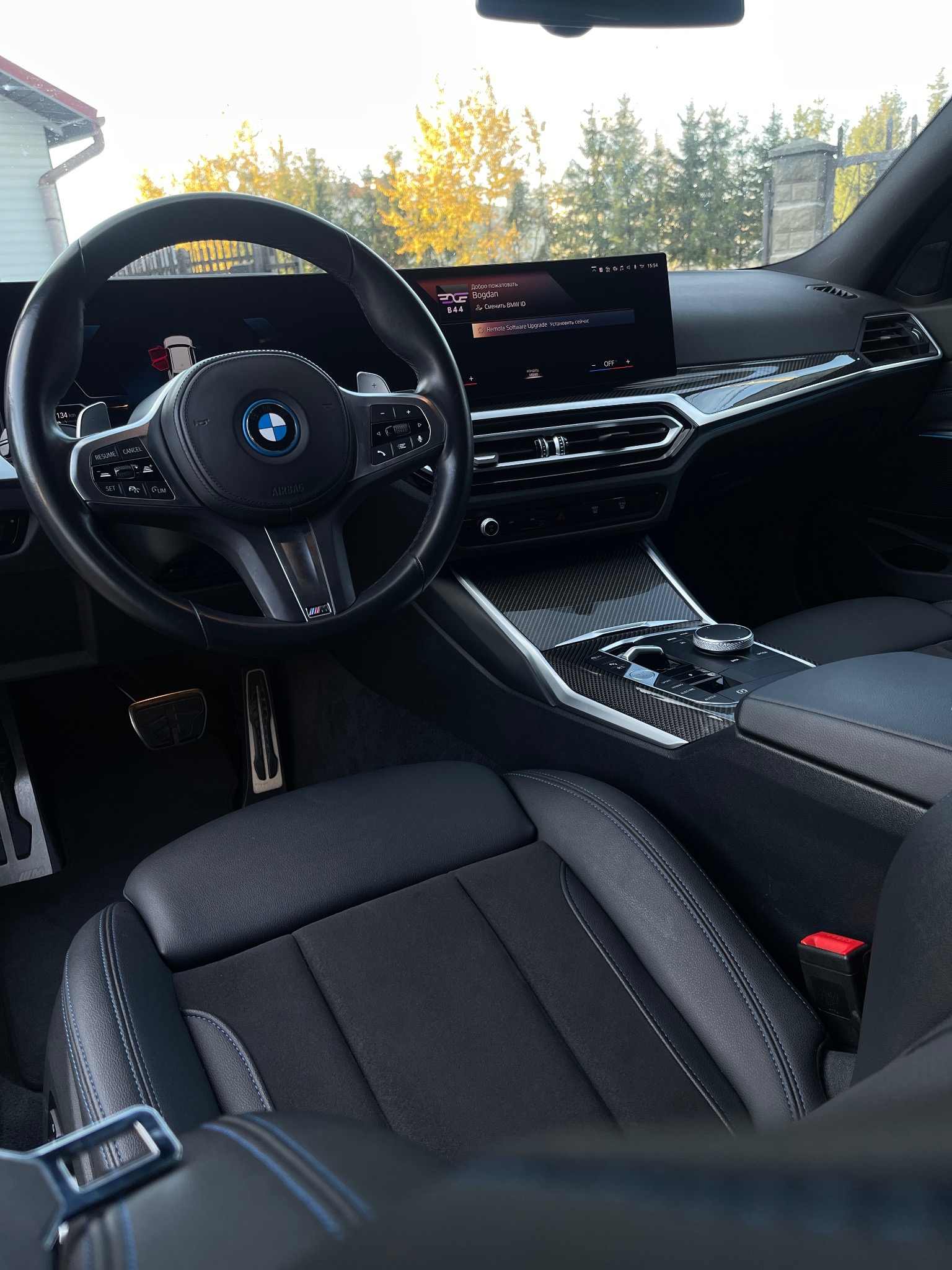 Wnętrze luksusowego samochodu BMW w Rzeszowie, widok na deskę rozdzielczą, kierownicę z logo, skórzane fotele z niebieskimi przeszyciami oraz elementy wykończenia z włókna węglowego.