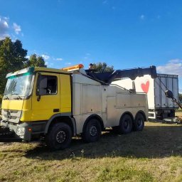 Rendgen Mechanik Mobilny Elektryk Samochodowy Gdańsk Gdynia Sopot - Żółto-srebrny holownik z wysięgnikiem podczepiony do białej naczepy z czerwonym sercem, na tle błękitnego nieba i zieleni drzew.