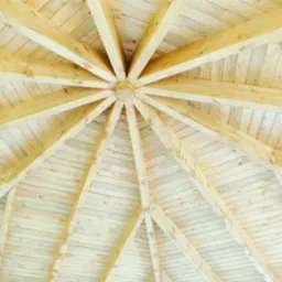 Wnętrze dachu altany z jasnego drewna, widok z dołu ukazujący symetryczny układ belek i desek.