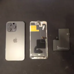 Rozłożony iPhone 14 Pro Max z widoczną baterią, obudową i elementami wewnętrznymi na czarnym tle.