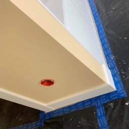 Deco-Bor Tomasz Borkowski - Pomarańczowy sufit z wykończeniem i otworem na oświetlenie, zabezpieczony taśmą malarską i folią ochronną.