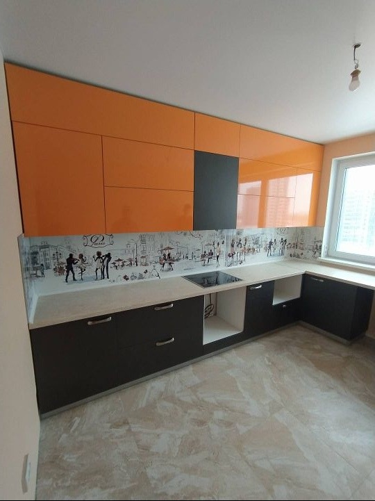 Nowoczesna kuchnia z pomarańczowymi szafkami górnymi i ciemnoszarymi dolnymi, ozdobiona panelem ściennym z motywem Paryża, widok na płytę indukcyjną i okno.