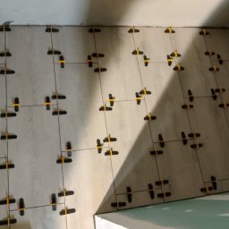 Czapkbud - Płytki podłogowe imitujące drewno, ułożone z użyciem systemu poziomowania płytek (klipsy i kliny), widok z góry, fragment ułożonej powierzchni.