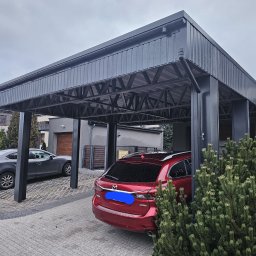 TB SESTAL SPÓŁKA CYWILNA JUSTYNA IBROM-JASIŃSKA, DAMIAN JASIŃSKI - Nowoczesny, grafitowy carport z blachy trapezowej, z widoczną konstrukcją nośną, chroniący dwa zaparkowane samochody Mazda na posesji z kostki brukowej.